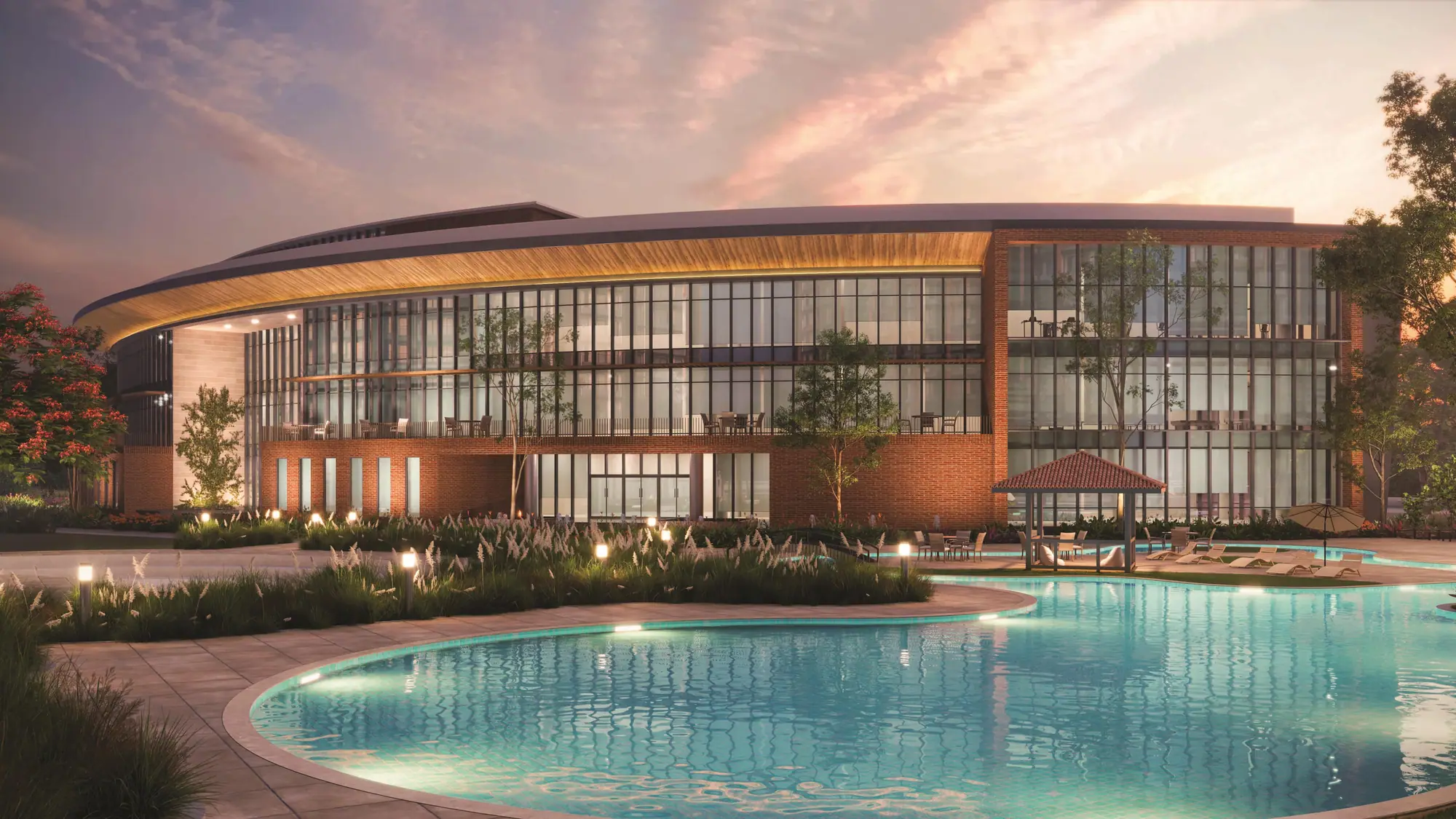 The clubhouse at dusk with its curved timber canopy and free-form pool