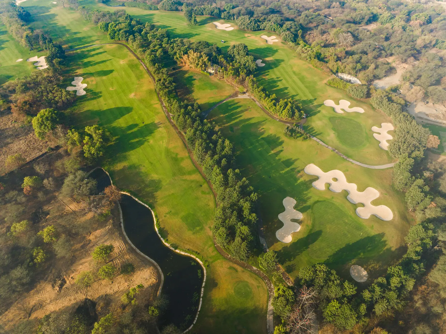 Aerial view of the golf course, bunkers and water body at Karma Lakelands
