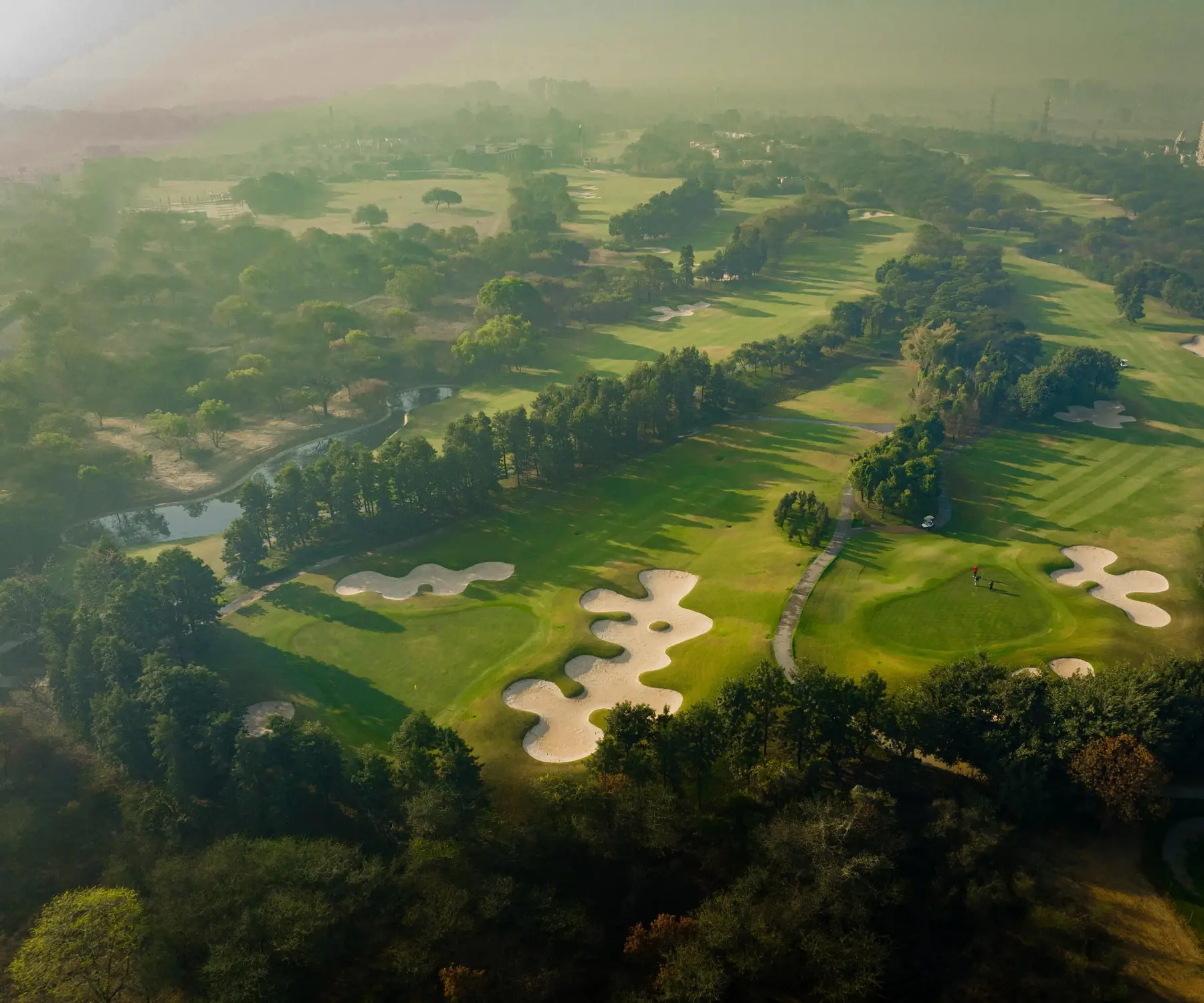 Golf greens framed by mature trees at Karma Lakelands